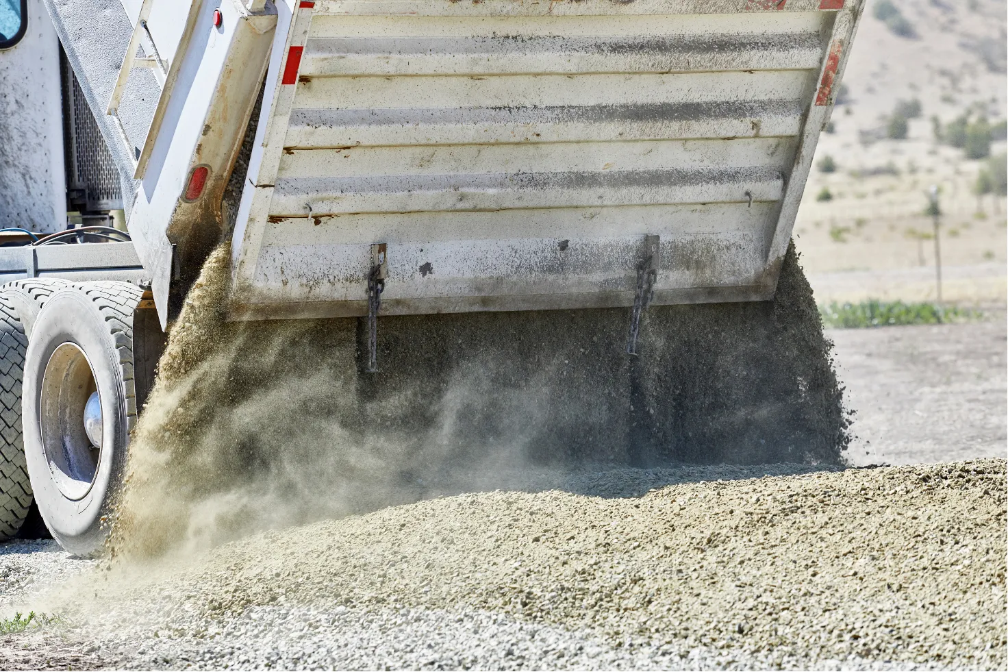 A dump truck unloads gravel onto the ground at a New Jersey construction site, where Asphalt Worxx LLC provides expert asphalt services.