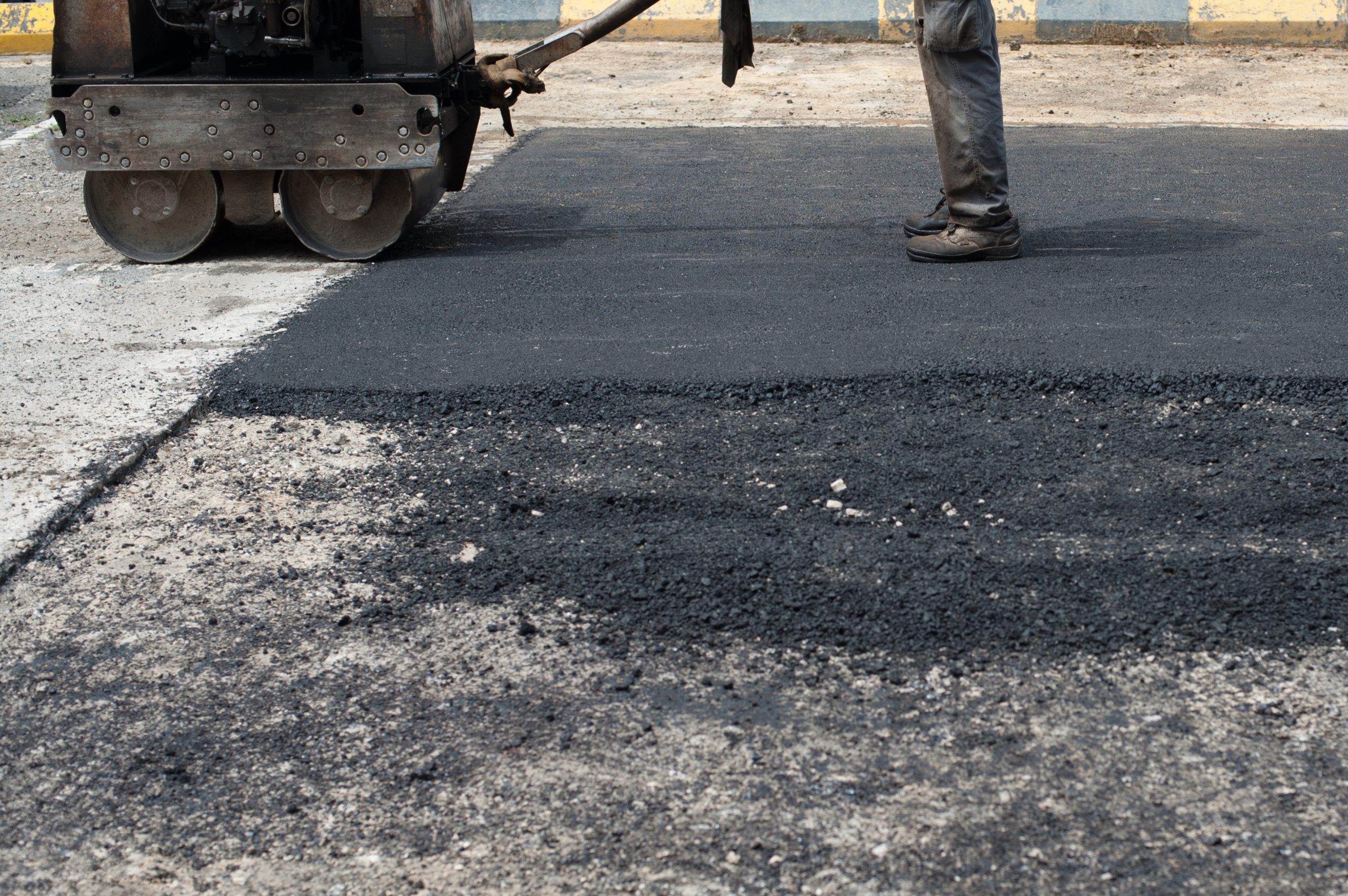 Nazir AZHARI Photography A worker from Asphalt Worxx LLC stands by a steamroller, paving fresh asphalt on a road under construction in Toms River.